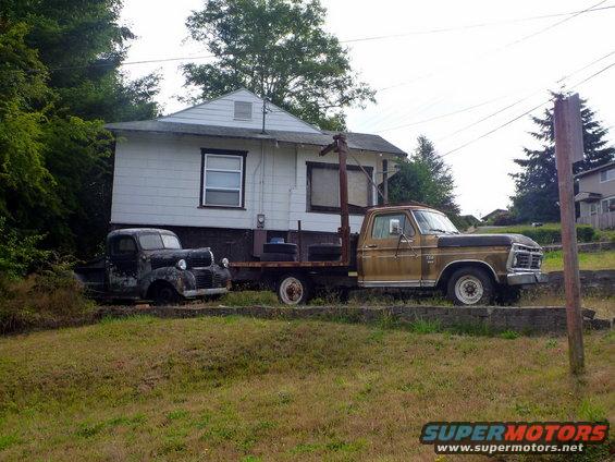 Truck with a camper shell parked in a grassy area with trees