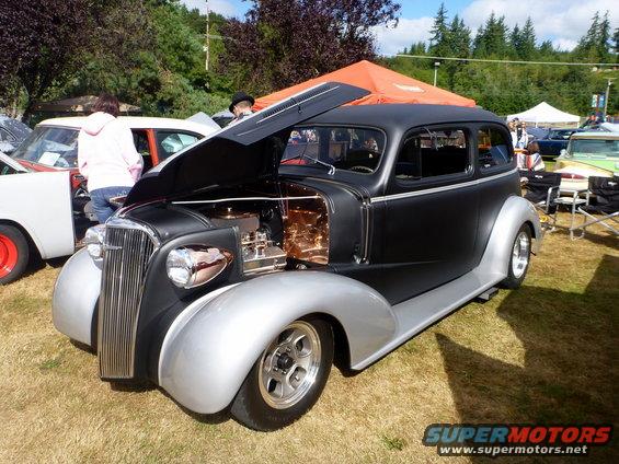 Custom hot rod sedan with hood open, parked outdoors