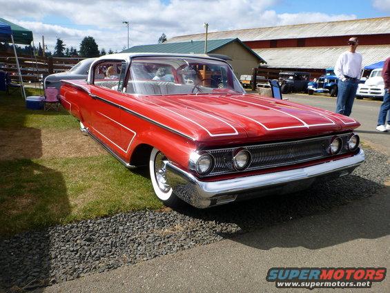 Red 1969 Lincoln Continental with white wall tires, viewed from the front three-quarter angle