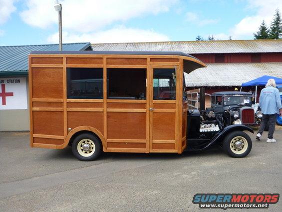 Custom vehicle with wood paneling on the rear section and a dark front cab