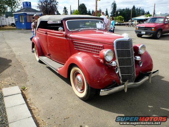 Red 1936 convertible with whitewall tires and black top, seen from a 3/4 front angle