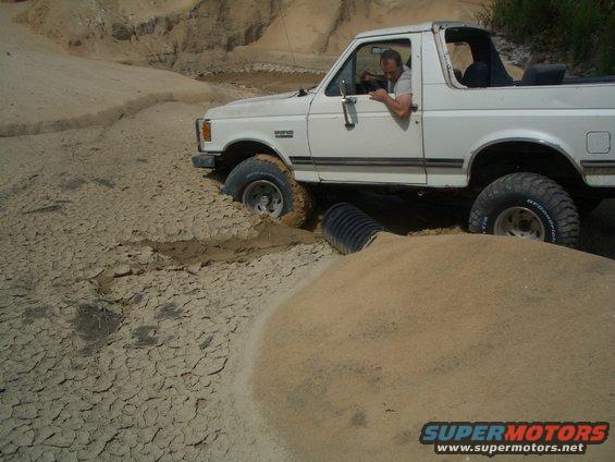 White SUV stuck in mud with a pipe under its chassis