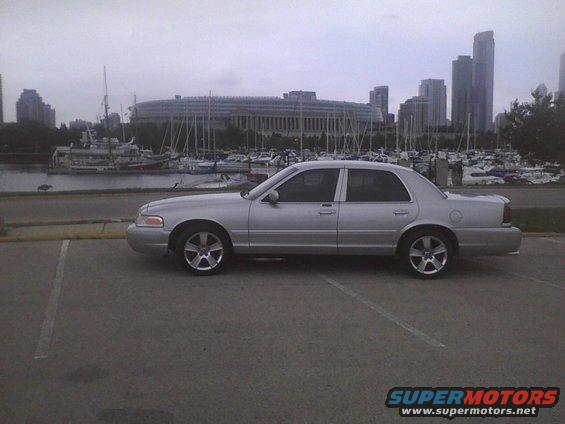 Silver 2003 Ford Crown Victoria side view parked by a marina