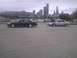 2003 Ford Crown Victoria - Two sedans are parked side-by-side near a harbor with boats and a city skyline.