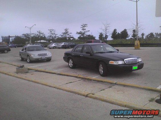 Black 2003 Ford Crown Victoria parked next to a silver one in a parking lot