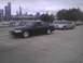 2003 Ford Crown Victoria - Two Ford Crown Victorias are parked in a lot with a marina and city skyline behind them.