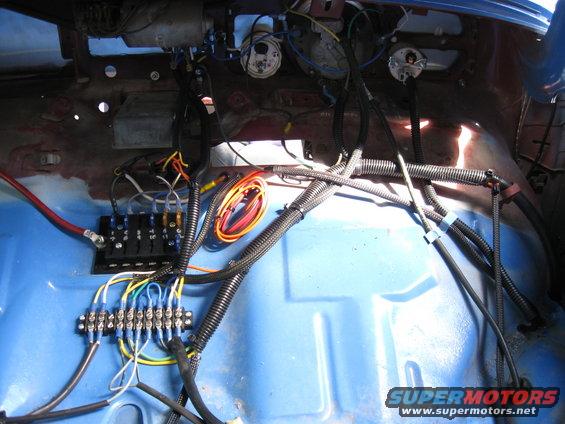 Close-up of a vehicle's interior wiring harness, fuse box, and terminal blocks
