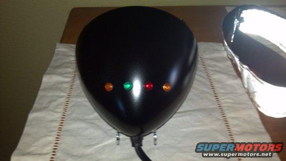 Black motorcycle headlight assembly with four indicator lights: orange, green, red, orange