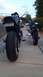 1996 Buell S1 Lightning w/Fairing - Two motorcycles are parked on a sidewalk. The closest one is viewed from the rear, showing flame decals on its tail section and a license p…