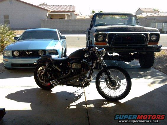 2006 Ford Mustang parked next to a motorcycle and an older Ford pickup truck