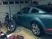 2006 Ford Mustang - A blue coupe and a motorcycle are parked side-by-side inside a garage.