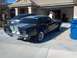 2006 Ford Mustang - A classic black Ford Mustang with silver racing stripes is parked in front of a house.