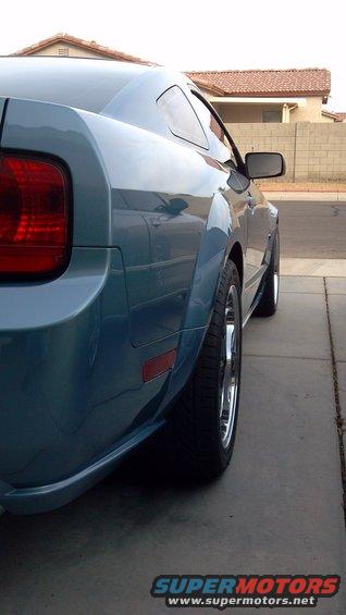 Rear quarter panel and wheel of a blue Ford Mustang, viewed from the side