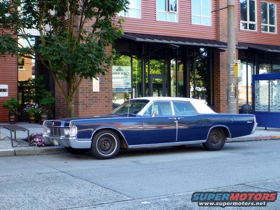 Blue 1969 Lincoln Continental parked on street, white roof, chrome trim