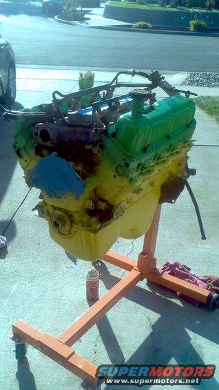 engine on an orange stand, painted green and yellow