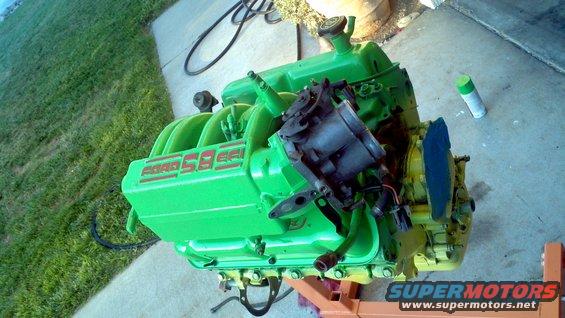 Green Ford 5.8L engine on an orange stand, with a carburetor and intake manifold visible