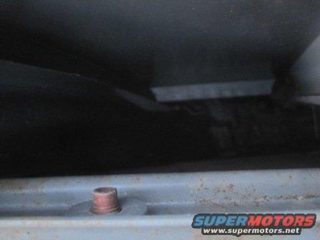 Close-up of a rusty bolt and dark interior panel