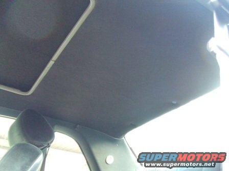 Dark grey car interior ceiling with a sunroof frame and a headrest visible