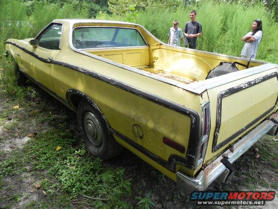 Yellow 1974 Ford Ranchero with black trim, seen from the rear three-quarter angle, parked outdoors