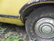 1974 Ford Ranchero - The wheel well of a yellow vehicle shows rust and peeling trim around the tire.