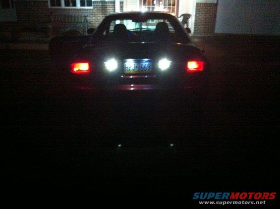 red convertible sports car with taillights on, license plate visible