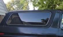 Side view of a dark-colored vehicle's rear window with chrome trim