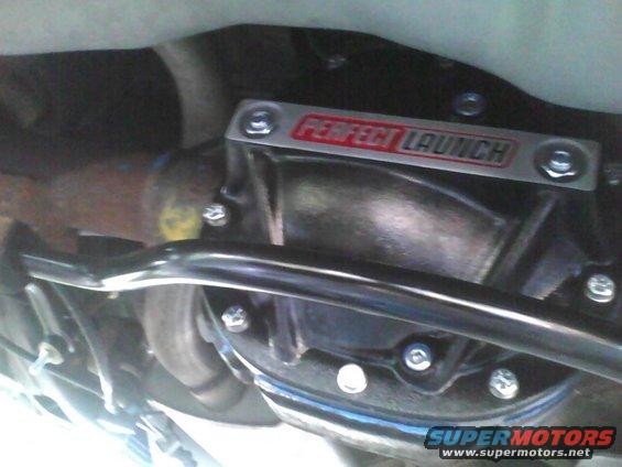 Rear differential housing with a 'PERFECT LAUNCH' aftermarket cover installed. Some exhaust components are visible