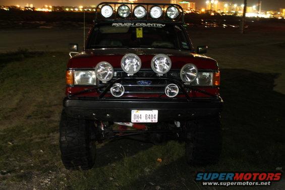 Front view of a red 1990 Ford Bronco with a light bar on the roof and extra lights on the bumper