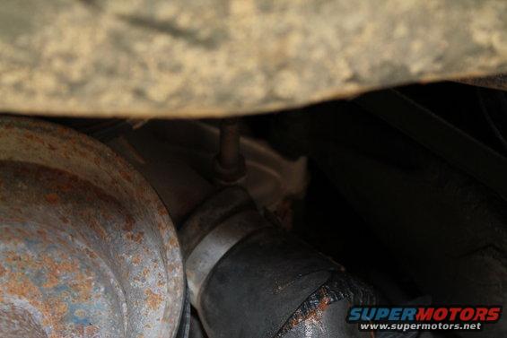 Underside view of rusty metal and hoses, with SuperMotors logo