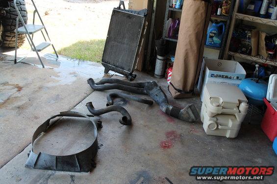 Radiator and engine hoses laid out on a concrete floor next to a ladder and a tire