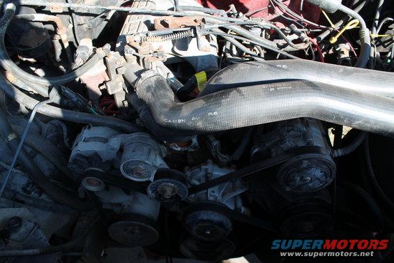 Engine bay with hoses, belts, and alternator visible. Text on hose reads 'CA11BN AU R6'