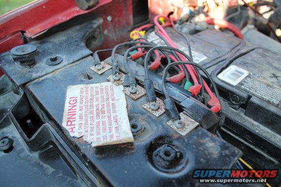 Engine bay with two batteries and red and black wiring connected to terminals
