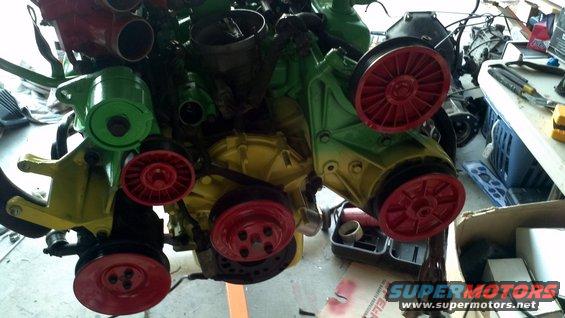 Engine components painted green, yellow, and red with belts and pulleys