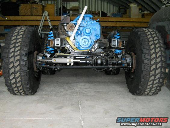 Off-road vehicle chassis with large tires and a blue engine, front view