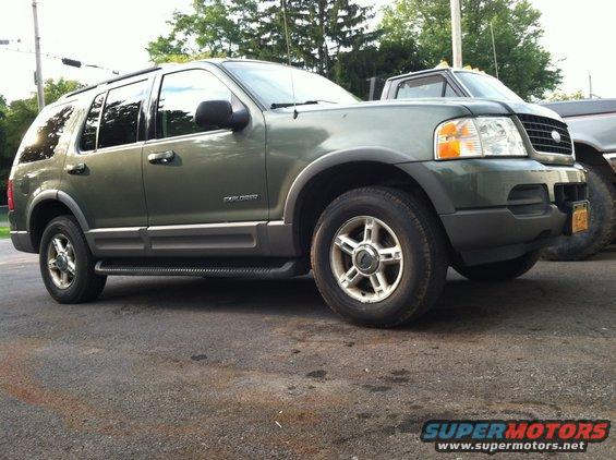 Green 2002 Ford Explorer parked next to a pickup truck