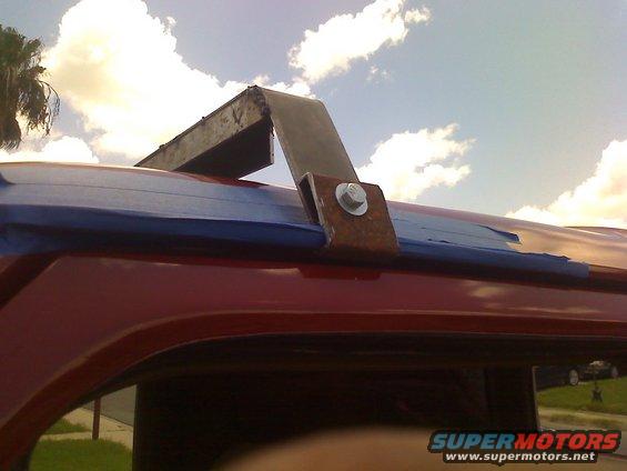 Red vehicle roof with custom metal rack attachment secured by bolt