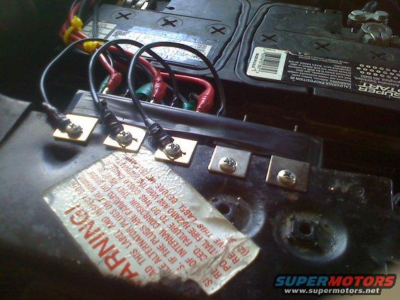 Car battery terminals with red and black wires connected to square metal plates