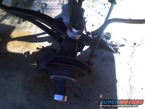 Close-up of a vehicle's front suspension assembly, showing the brake rotor and hub
