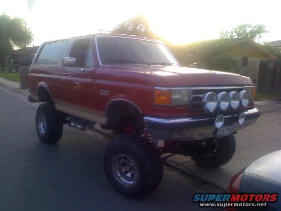 Red 1990 Ford Bronco with lifted suspension and four fog lights on the front bumper