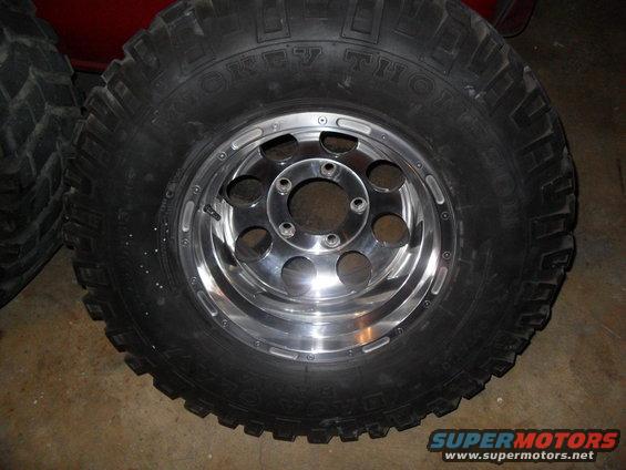Tire with 'MICKEY THOMPSON' text and a chrome alloy wheel with six lug holes