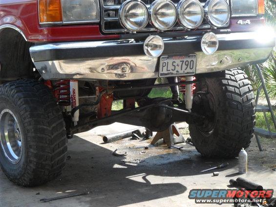 Red lifted truck front end with off-road tires, spotlights, and license plate PLS 790