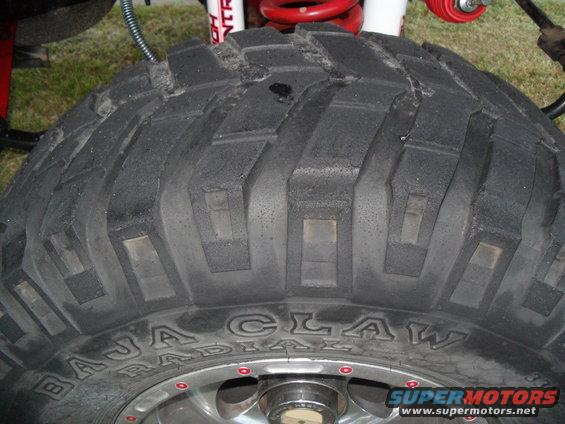 Tire with "BAJA CLAW RADIAL" text, red shock absorber, and "SUPERMOTORS" logo