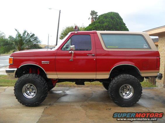 Red 1990 Ford Bronco side view with lifted suspension and large tires