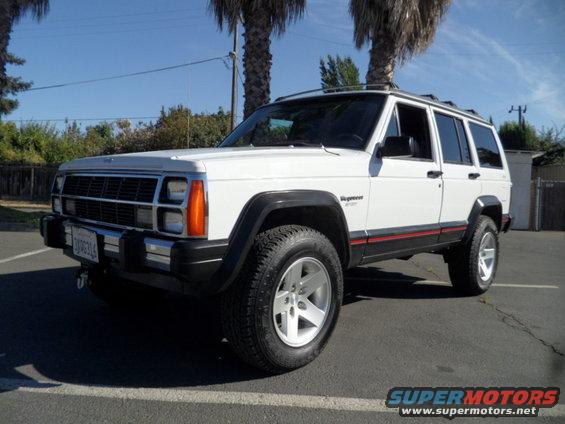 White 1994 Jeep Cherokee parked on asphalt, front 3/4 view, with red stripe along the lower body