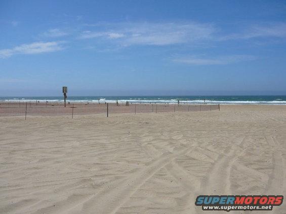 Beach scene with fence and ocean under blue sky