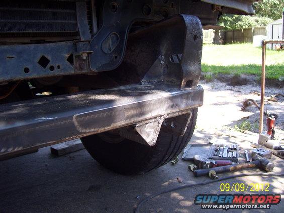 Custom bumper being welded onto a vehicle frame, with tools on the ground