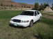 2006 Ford Crown Victoria - White 2006 Ford Crown Victoria parked in a field with a teepee and hills in the background.
