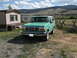 1996 Ford Bronco - A green Ford Bronco is parked in a grassy area next to a trailer home with a wooden fence and hills in the distance.