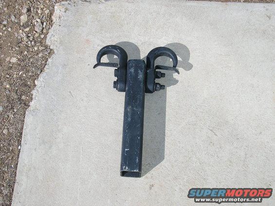 Black tow hitch receiver with two hooks, sitting on concrete