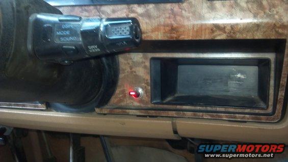 Dashboard interior showing an aftermarket radio slot and a toggle switch with a red LED. Controls on a stalk near the steering wheel have 'DSP', 'MODE', and 'SOUND' labels